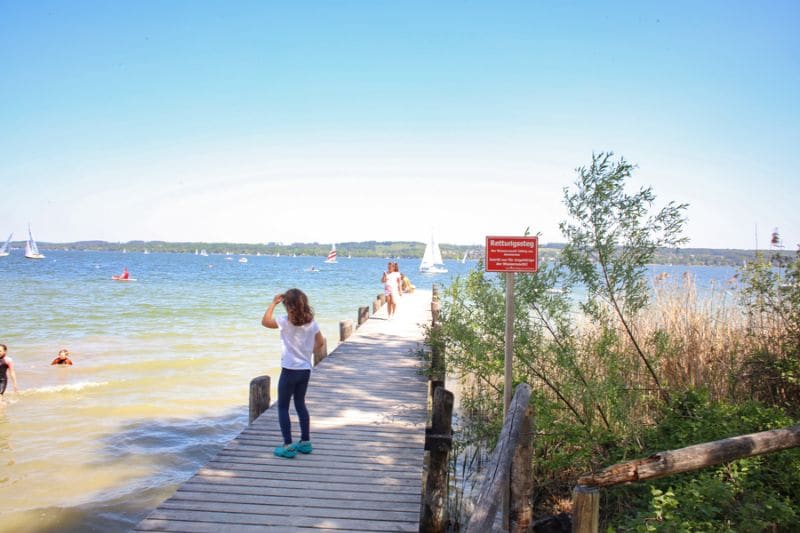 Kind steht auf einem Steg am See