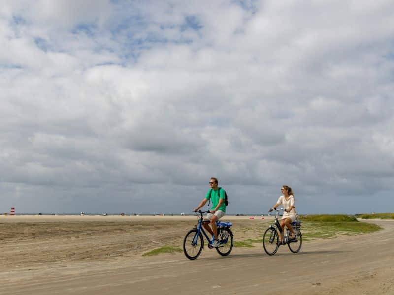 Mann und Frau auf dem Fahrrad entlang eines Sandstrandes 