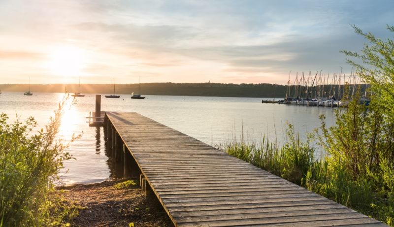 Camping im Fünfseenland: Ein Steg am Ammersee bei Sonnenaufgang